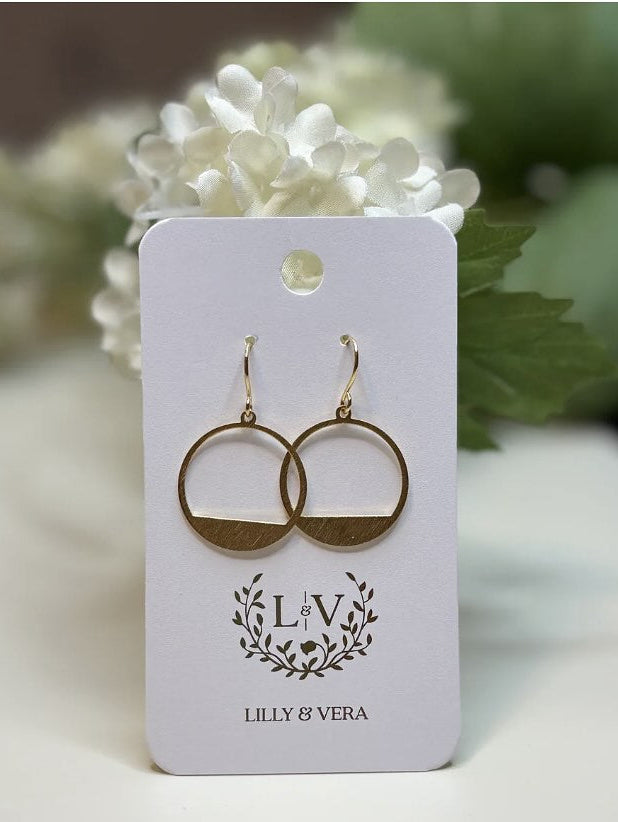 Gold hoop earrings on a 'Lilly & Vera' branded card with flowers in the background
